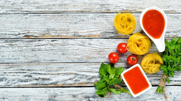 Pasta secca e ingredienti su fondo di legno bianco Vista dall'alto Spazio libero per il testo