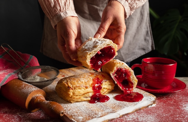 Pasta sfoglia dessert marmellata rossa mano viburno ciliegia tazza caffè sfondo nero