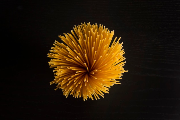 Pasta spaghetti cucina italiana cibo. cibo per spaghetti lungo giallo crudo su sfondo nero in alto vi