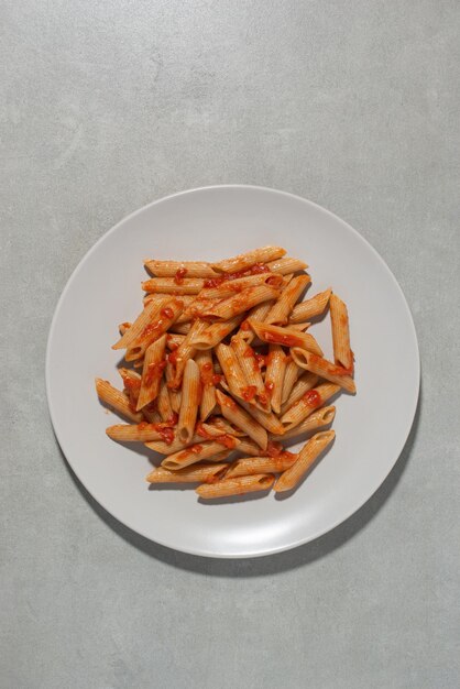 Pasta su una forchetta con pomodori e formaggio in un piatto su sfondo grigio