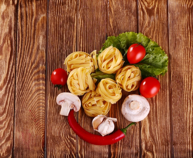 Pasta sui precedenti di legno con il pomodoro, il pepe, l'olio d'oliva, i funghi e la lattuga