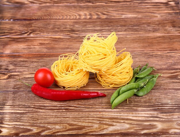 Pasta sulla parete di legno con pomodoro, lattuga al pepe e pepe