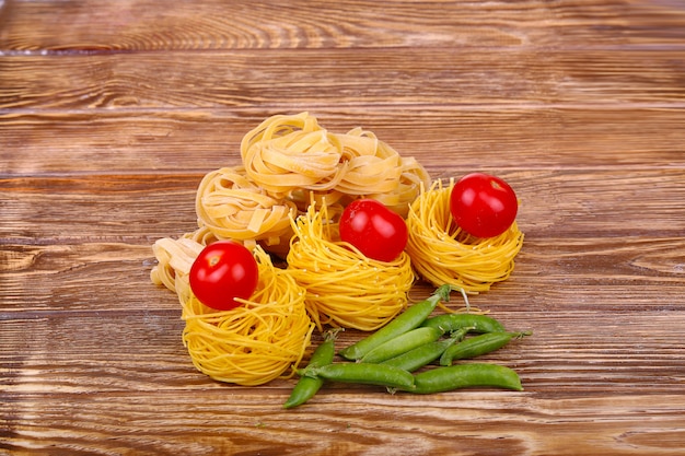 Pasta sulla parete di legno con pomodoro, pepe di lattuga, olio d'oliva e pepe