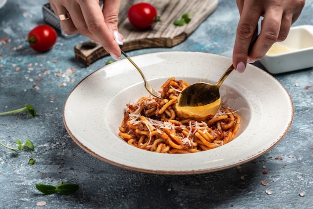 Pasta tradizionale italiana alla bolognese con salsa di pomodoro e carne macinata servita in un piatto con parmigiano. Sfondo di ricetta alimentare. Avvicinamento.