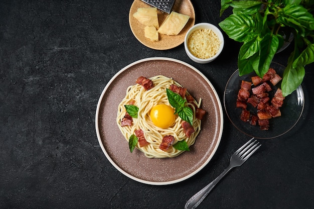 Pasta tradizionale italiana alla carbonara con pancetta e tuorlo d'uovo su piatto su fondo scuro top