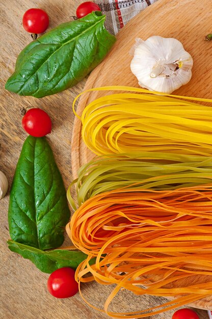 Pasta variopinta del fettuccine ed ingredienti di cottura sulla tavola di legno