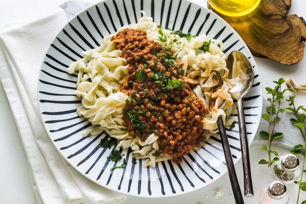 Pasta vegana con lenticchie e salsa di pomodoro in un piatto sul tavolo