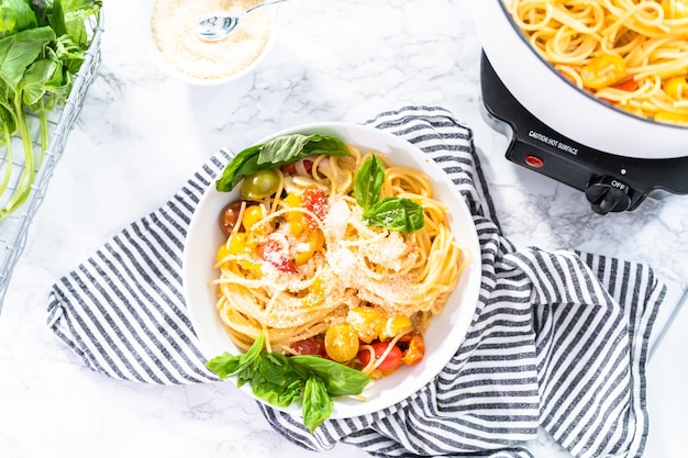 Pasta vegetariana con pomodorini e basilico fresco su un piatto bianco.