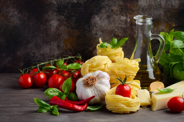 Pasta, verdure, erbe e spezie per cibo italiano sullo sfondo in legno.