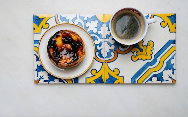 Pastel de nata. Dolce tradizionale portoghese, crostata di uova e tazza di caffè su piastrelle azulejo tradizionali su sfondo di marmo. Vista dall'alto