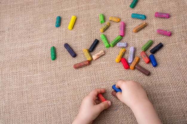 Pastelli a colori usati e una mano per bambini che ne tiene uno