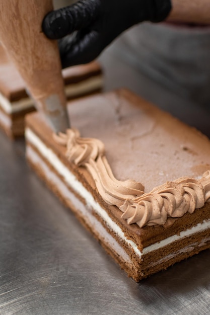 Pasticcere che decora la torta usando un sac à poche