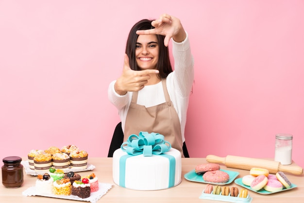 Pasticcere con una grande torta in un tavolo messa a fuoco faccia