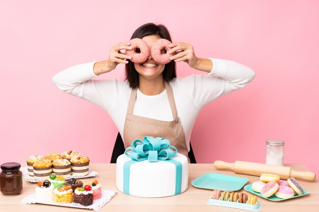 Pasticcere con una grande torta in una tabella sopra la parete dentellare isolata