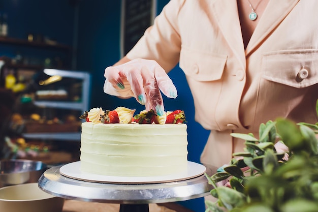 Pasticcere decorato con frutti di bosco una torta di biscotti con crema bianca La torta si trova su un tavolo di legno Il concetto di pasticceria fatta in casa per cucinare torte