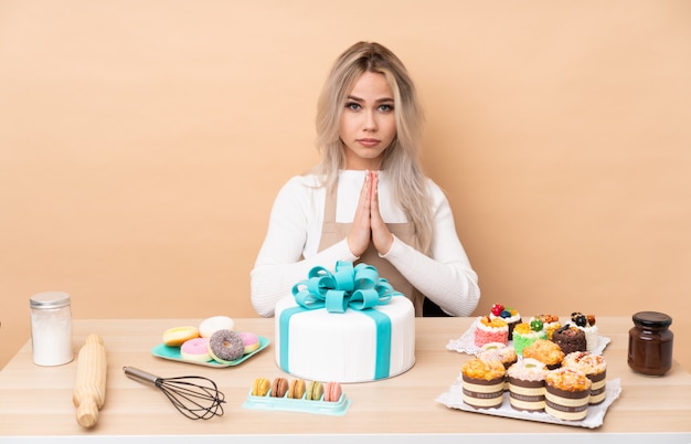 Pasticcere dell'adolescente con una grande torta in una supplica della tabella