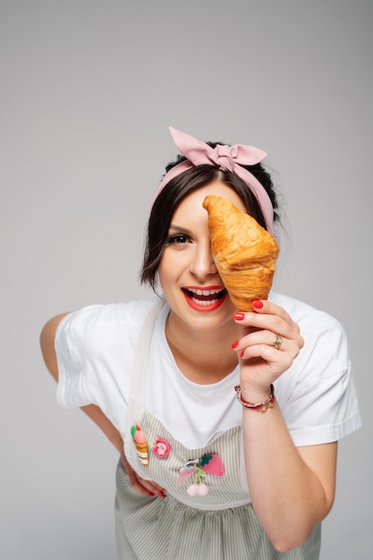 Pasticcere della ragazza che tiene il panino saporito fresco nelle mani