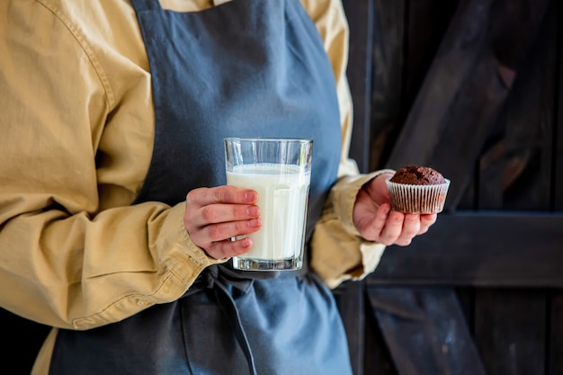 Pasticcere in grembiule tiene torta al cioccolato e latte