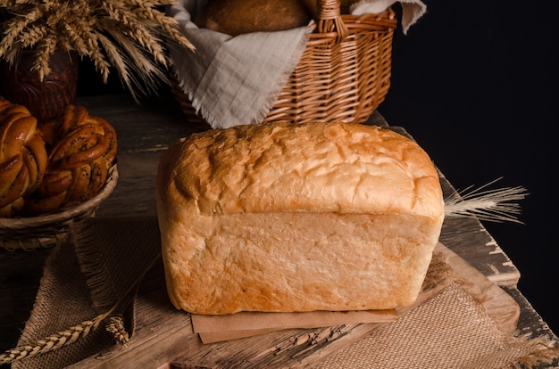 Pasticceria culinaria fresca appetitosa - pagnotta di pane bianco su fondo di legno