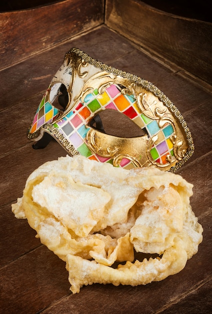 Pasticceria fritta del carnevale italiano con maschera veneziana.