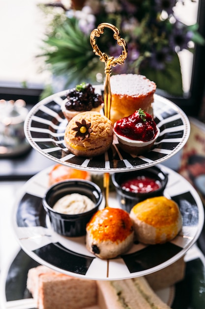 Pasticceria per il tè del pomeriggio con focaccine, panini e mini torte sul tavolo di marmo.