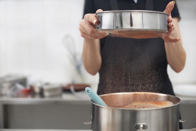 Pasticciere che indossa un'uniforme nera mentre lavora in pasticceria