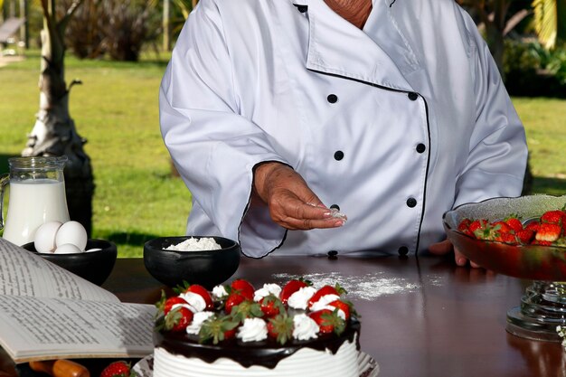 Pasticciere che prepara torte alle fragole con cioccolato