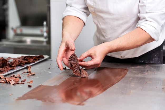 Pasticciere professionista che produce dolci al cioccolato nel negozio di dolciumi.