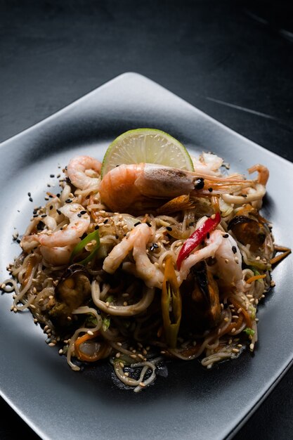 Pasto del menu del ristorante di cucina cinese. noodle gamberi gamberi frutti di mare e verdure su un piatto.