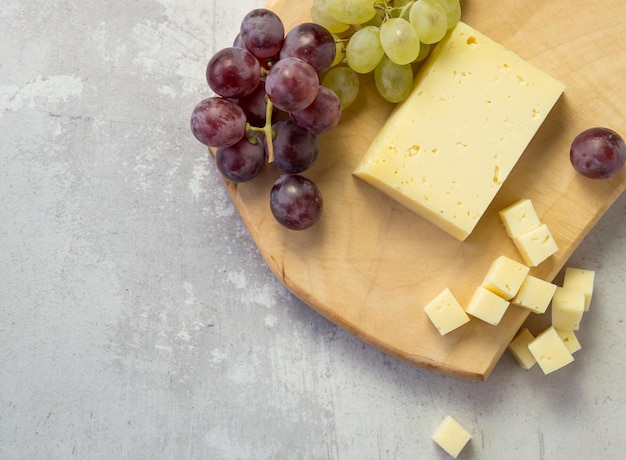 Pasto leggero con formaggio a fette accanto a un grappolo di uva bianca e rossa