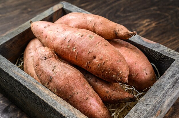 Patata dolce di batata cruda sulla tavola di legno