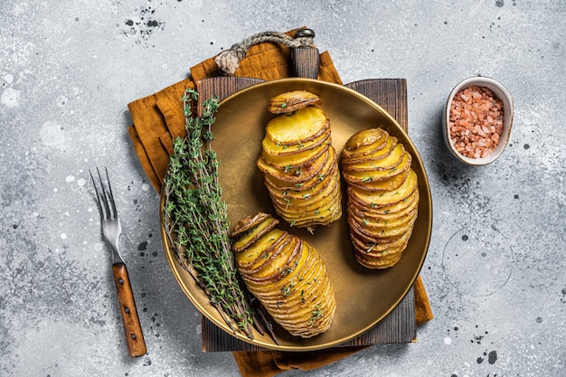 Patata Hasselback al forno con timo fresco e rosmarino Sfondo grigio Vista dall'alto