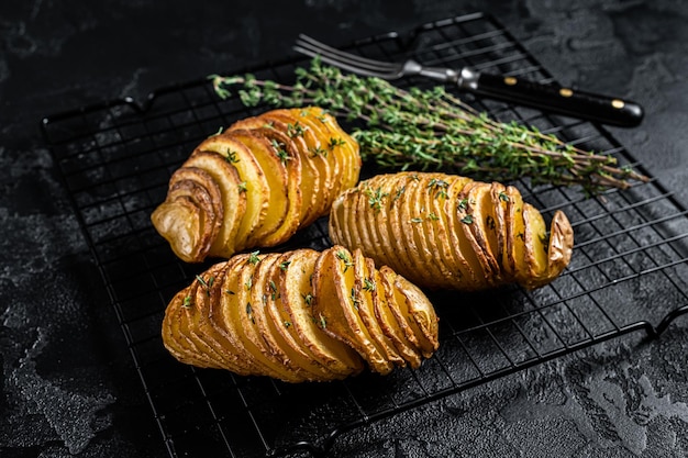 Patata Hasselback fatta in casa tradizionale americana con erbe fresche Sfondo nero Vista dall'alto