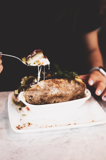 Patata kumpir al forno ripiena di formaggio salsiccia olive peperoni e mais