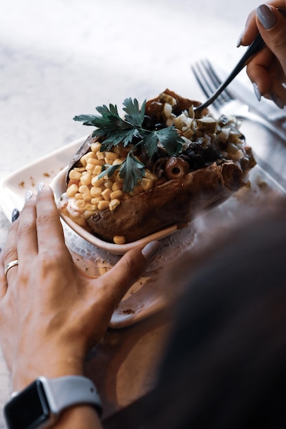 Patata kumpir al forno ripiena di formaggio salsiccia olive peperoni e mais