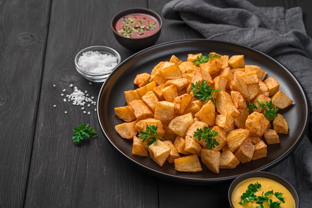 Patatas bravas con salse su sfondo nero. Antipasto spagnolo. Vista laterale, copia dello spazio.