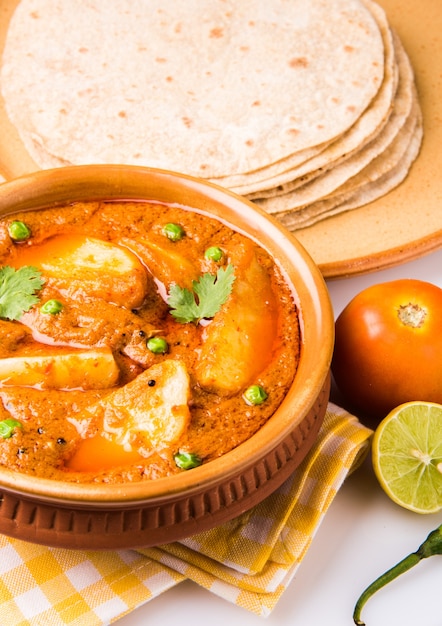 Patate al curry o aloo o Aaloo masala fry con piselli verdi, piatto principale indiano servito con pane piatto noto anche come chapati o Roti, messa a fuoco selettiva