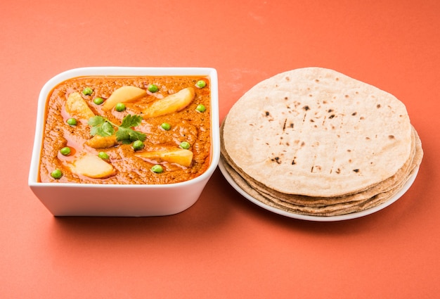 Patate al curry o aloo o Aaloo masala fry con piselli verdi, piatto principale indiano servito con pane piatto noto anche come chapati o Roti, messa a fuoco selettiva