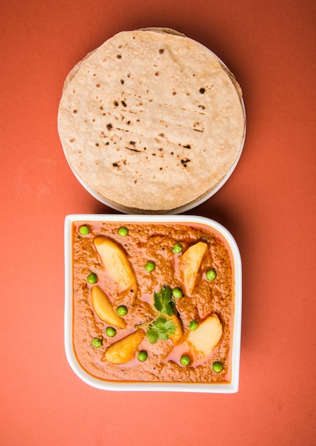 Patate al curry o aloo o Aaloo masala fry con piselli verdi, piatto principale indiano servito con pane piatto noto anche come chapati o Roti, messa a fuoco selettiva