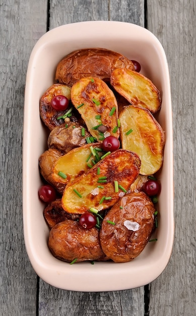 Patate al forno con bacche di mirtilli rossi su tavola di legno.