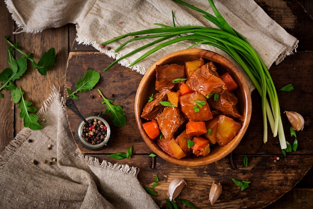 Patate al forno con manzo Bourguignon sulla vecchia tavola di legno in stile rustico