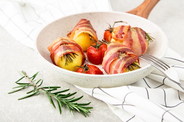 Patate al forno con pancetta, pomodori e rosmarino.