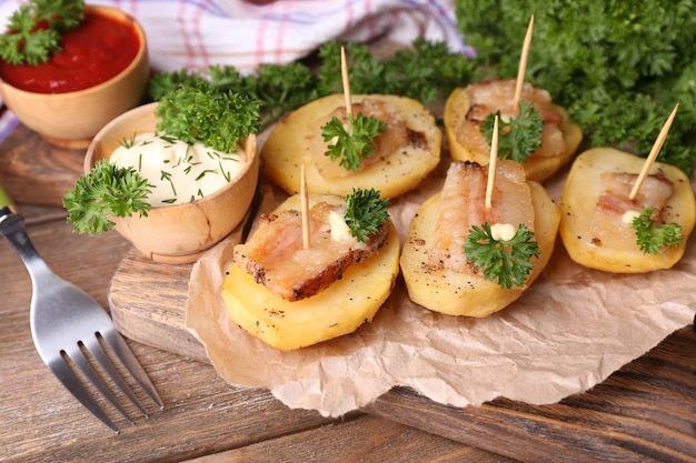 Patate al forno con pancetta sul tagliere di legno su fondo di legno