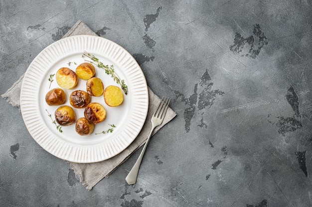 Patate al forno con set di rosmarino, su piastra, su sfondo grigio tavolo in pietra, vista dall'alto piatta, con spazio copia per il testo