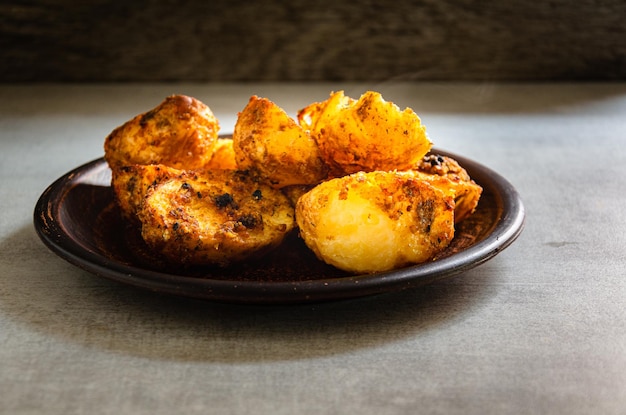 Patate al forno fatte in casa cotte alla contadina in un piatto di terracotta e un tovagliolo da cucina Casa c