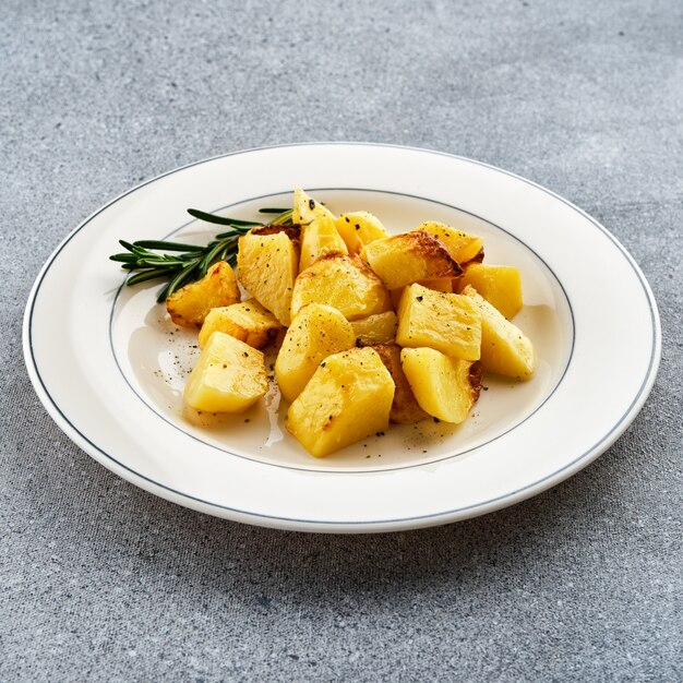 Patate al forno fritte con rosmarino su un piatto bianco.