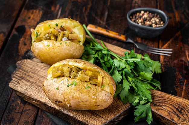 Patate al forno Kumpir ripiene di pancetta al formaggio cetriolo salato erbe e burro Fondo in legno Vista dall'alto