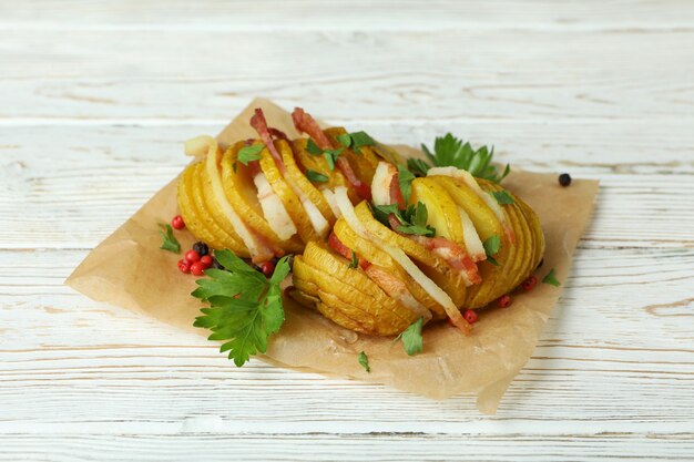 Patate al forno saporite sulla tavola di legno bianca.