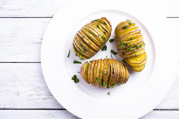 Patate al forno su un piatto bianco su un tavolo di legno bianco