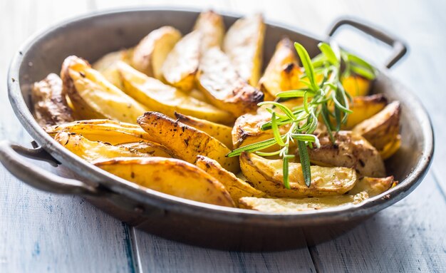 Patate arrosto in padella su tavola di legno.